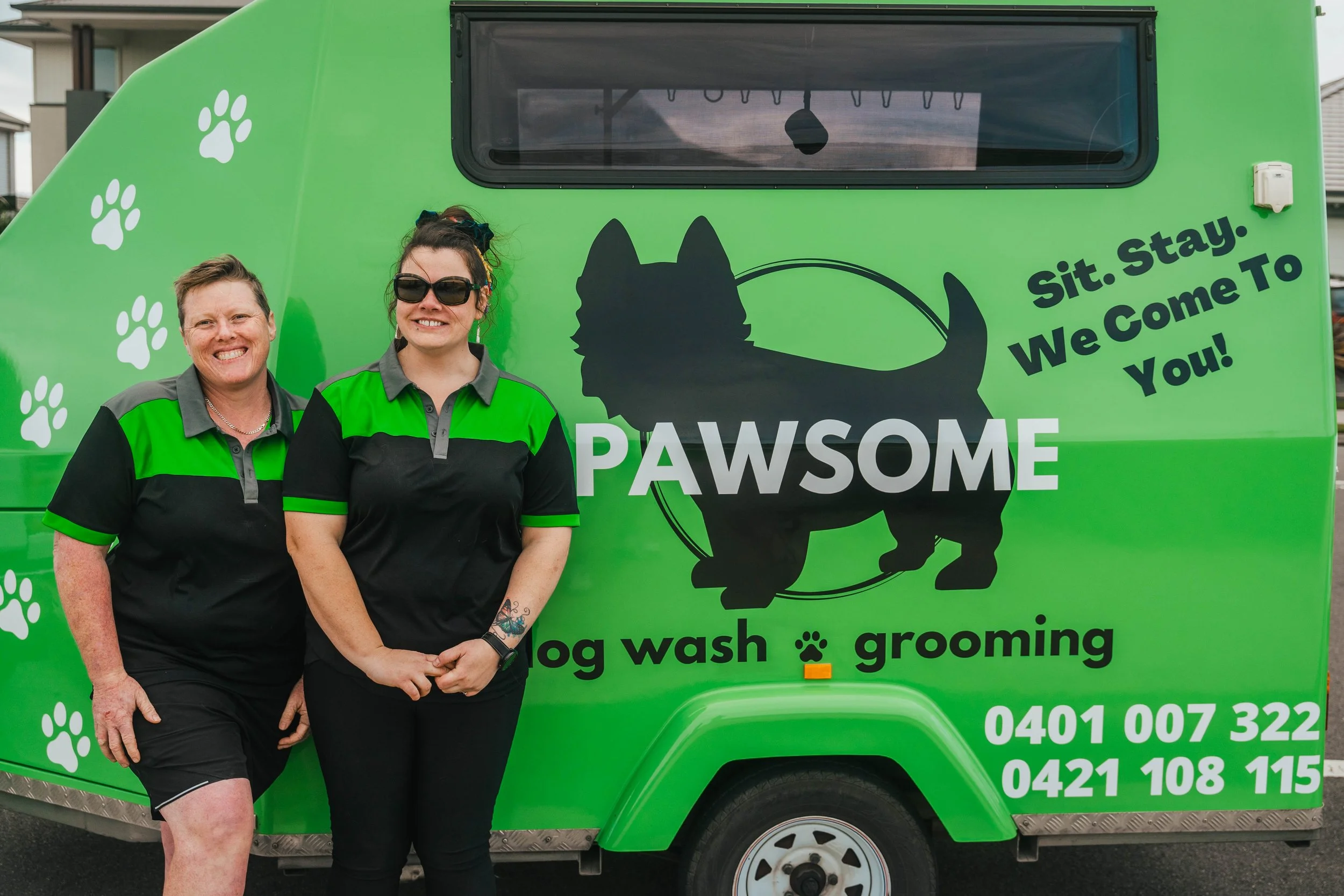 Megan and Bec beside the green Pawsome mobile grooming trailer